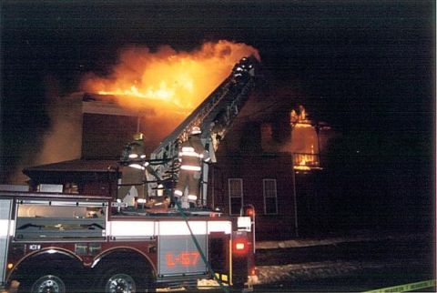 1989 Ford Bronco - Firefighters battle a blaze at a building with a ladder truck at the scene.