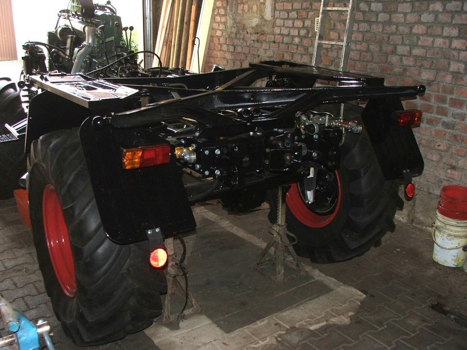 Tractor chassis on jack stands, rear view, large tires, exposed engine