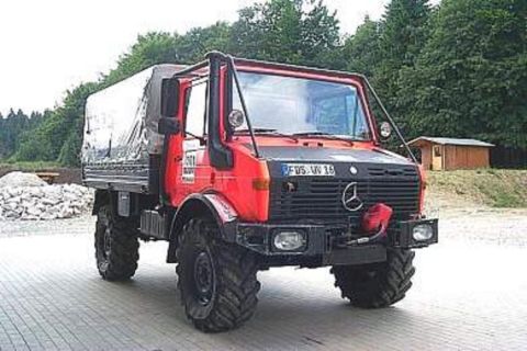 1991 Ford Bronco - This Mercedes-Benz Unimog truck is parked on a paved surface with trees in the background.