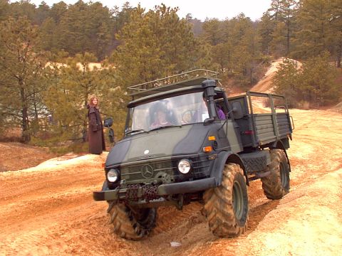 1991 Ford Bronco - This Mercedes-Benz Unimog is captured in a three-quarter front view while navigating a sandy, off-road terrain.