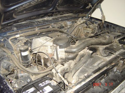 1988 Ford Bronco - Engine bay of a 1988 Ford Bronco, showing the engine, hoses, and battery.