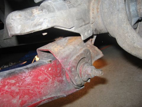 1974 Ford F-100 - Detail of a vehicle's suspension system, showing a worn red component and mounting hardware.