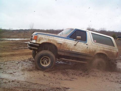 1978 Ford Bronco - This SUV is navigating a muddy terrain, kicking up dirt as it goes.