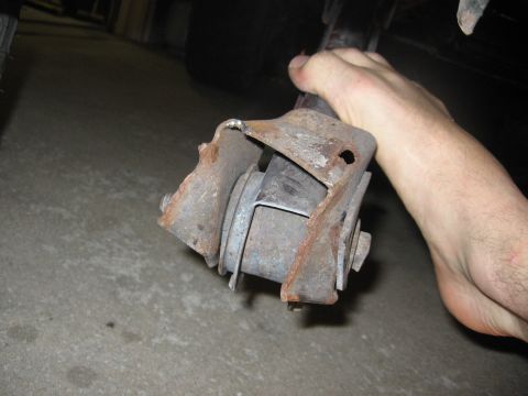 1974 Ford F-100 - A person holds a heavily rusted suspension part, showing signs of wear and tear.