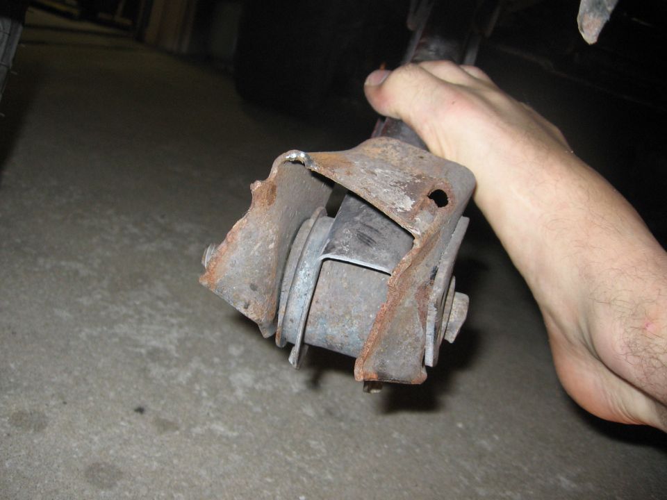 hand holding a rusty suspension component, possibly from a truck