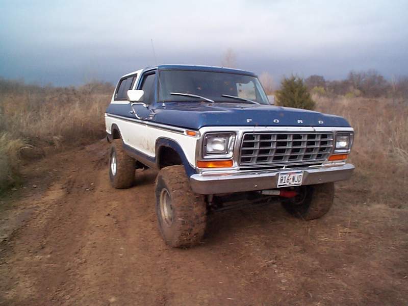 1978 Ford Bronco on a dirt road, blue and white paint, lifted suspension