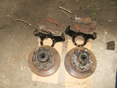 1994 Ford Bronco - Two brake rotor and caliper assemblies are laid out on cardboard, appearing to be parts removed from a vehicle.
