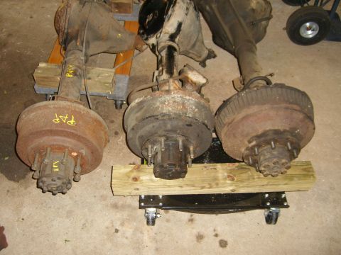 1994 Ford Bronco - Collection of vehicle axles, some with yellow markings, stored indoors.
