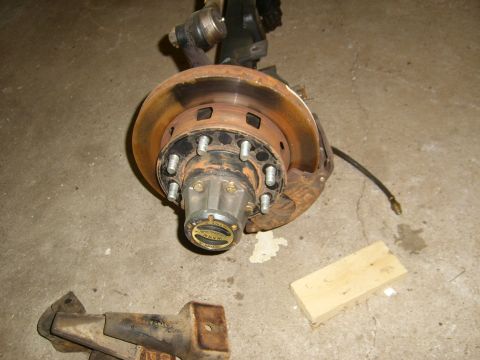 1994 Ford Bronco - Close-up of a vehicle's front axle assembly, showing the hub, brake rotor, and caliper bracket.