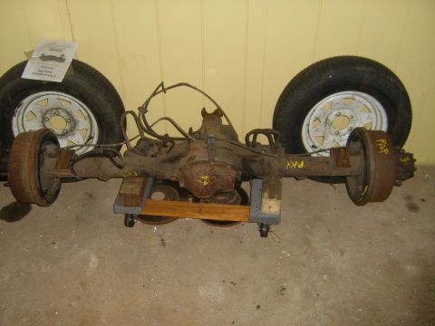 1994 Ford Bronco - A rear axle assembly, likely from a truck or SUV, is shown with two wheels and brake drums. Markings on the axle read 'PAY'.