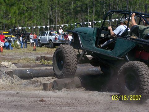 1989 Ford Bronco - Off-road vehicles tackle a log obstacle course during an event.