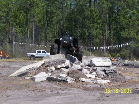 1989 Ford Bronco - Off-road vehicle navigates a challenging obstacle course with a pickup truck nearby.