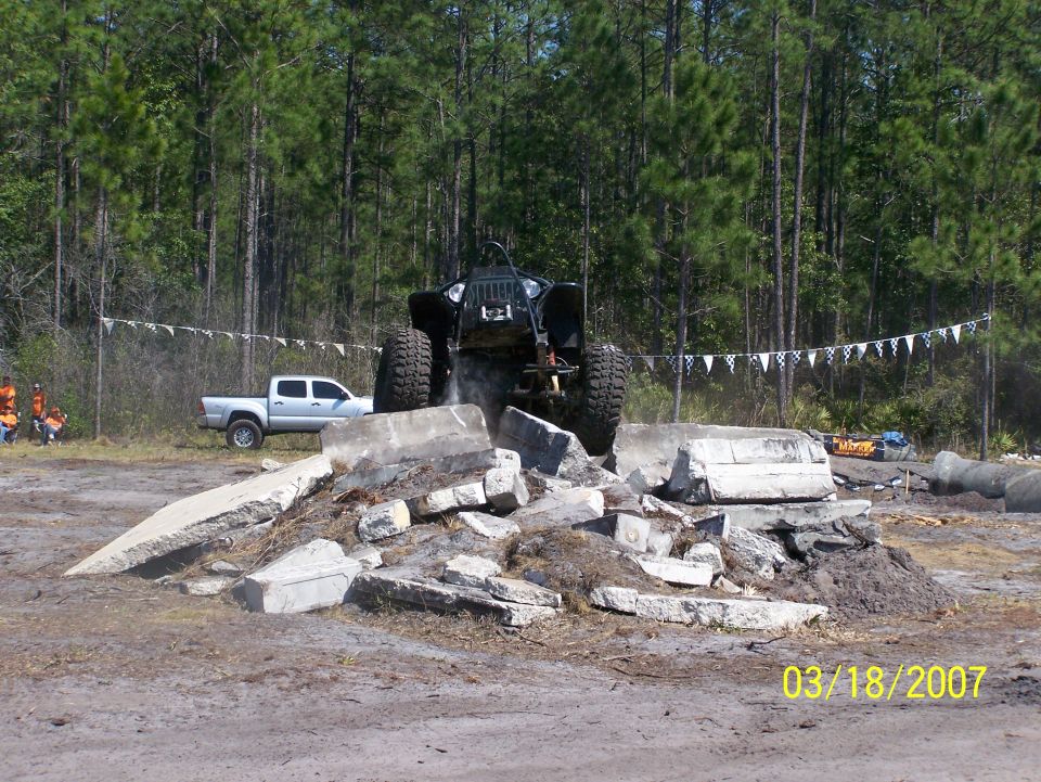 Off-road vehicle on concrete obstacle, silver pickup truck in background. Date stamp 03/18/2007