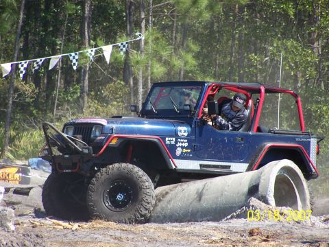 1989 Ford Bronco - A blue Jeep Wrangler navigates an off-road obstacle course with concrete pipes.