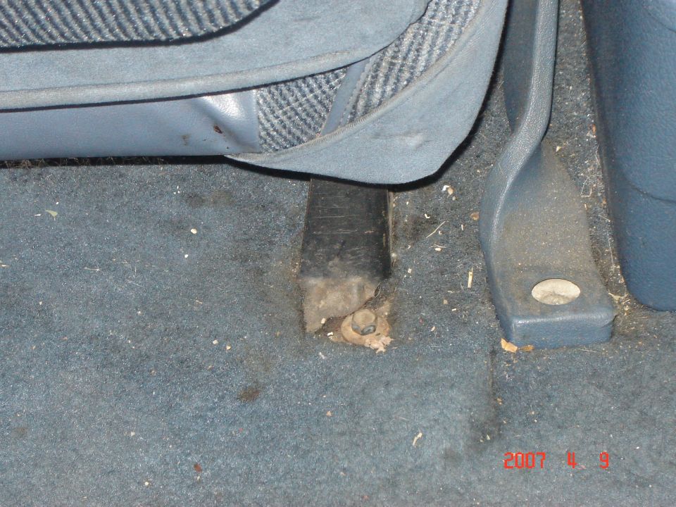 Seat mounting bracket and bolt on blue carpet under a blue seat in a Ford Bronco interior