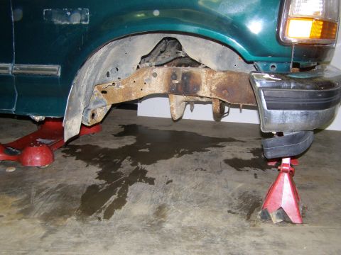 1993 Ford Bronco - The vehicle's frame shows significant rust and is elevated on jack stands for maintenance.