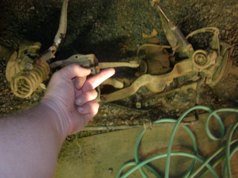 1993 Ford Bronco - Close-up of vehicle suspension components, with a hand indicating a specific part.
