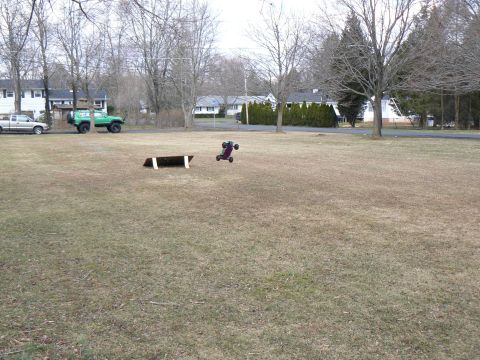 1994 Ford Bronco - Two parked vehicles are visible on a street, while a remote-controlled car performs a jump in a nearby field.