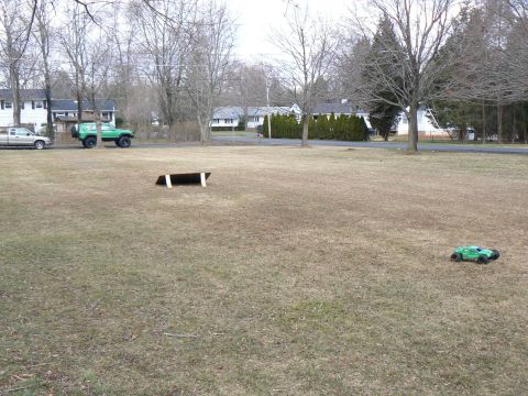 1994 Ford Bronco - A green off-road vehicle and a remote-controlled car are parked on a dry, grassy field with houses in the distance.