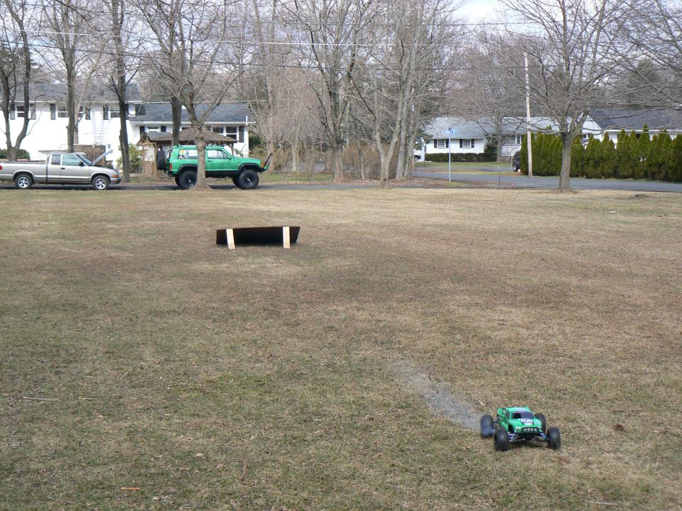 Silver pickup truck with hood open, green lifted SUV, and green remote control car on grassy field