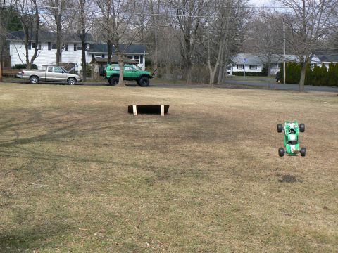 1994 Ford Bronco - Two vehicles are parked in a yard, one a pickup truck and the other a green off-road vehicle.
