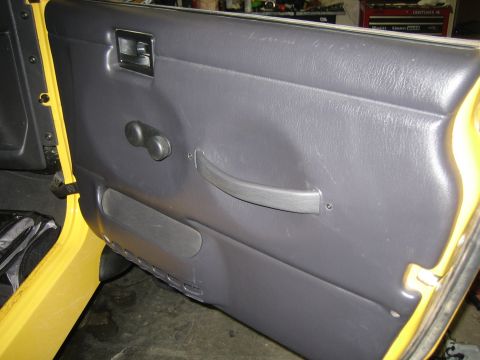 2001 Jeep Wrangler - Close-up of the interior door panel, showing the manual window crank and storage pocket.