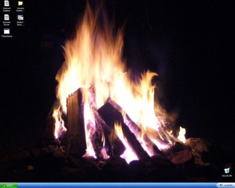 1991 Ford Probe - A campfire burns brightly in the dark, illuminating logs and surrounding ground.