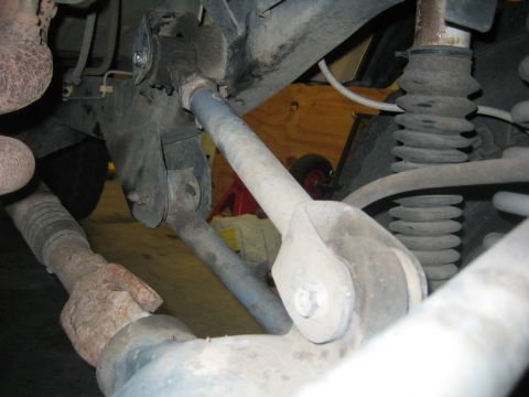 2001 Jeep Wrangler - Undercarriage view of a vehicle's rear suspension system, showing various metal components and a rubber shock boot.