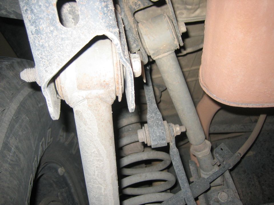Close-up of rear suspension parts, including a coil spring, shock absorber, and part of the exhaust system