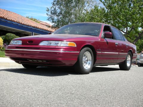 1992 Ford Crown Victoria - A maroon 1992 Ford Crown Victoria sedan is parked on a street, with another vehicle visible in the background.