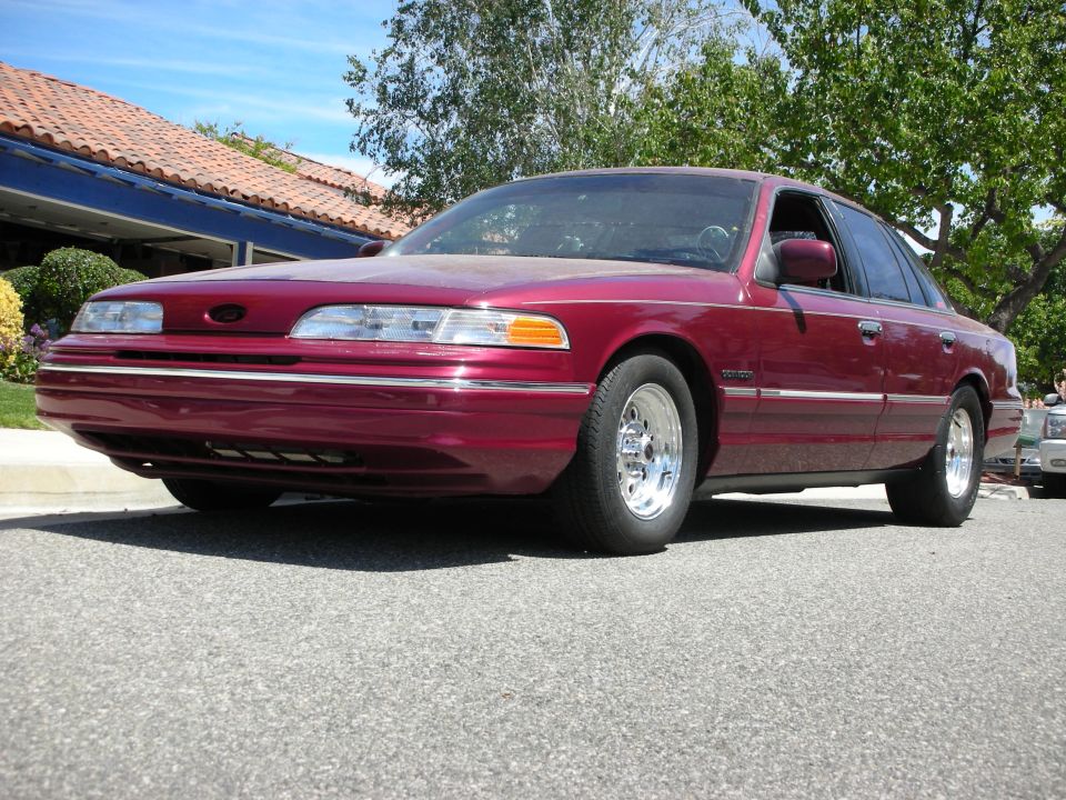 Maroon 1992 Ford Crown Victoria sedan with chrome wheels parked on asphalt