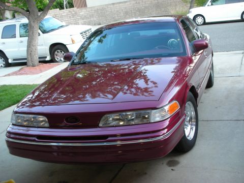 1992 Ford Crown Victoria - A maroon 1992 Ford Crown Victoria is parked in a driveway, with a white SUV and a white Cadillac Escalade also visible.