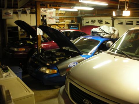 1992 Ford Crown Victoria - Multiple Ford vehicles are in a garage, with one Crown Victoria having its hood open.