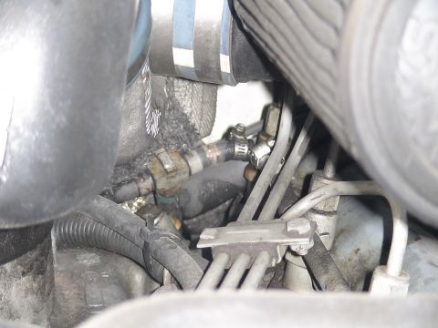 1993 Ford C-350 (Centurion Conversions) - Close-up view of engine bay components, including hoses and metal tubing, with visible grime and clamps.