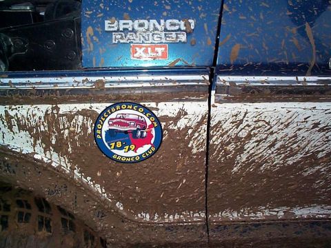 1978 Ford Bronco - A close-up of a heavily mud-covered 1978 Ford Bronco Ranger XLT, showing its side panel and a club sticker.