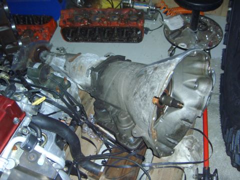 1974 Ford Bronco - Close-up of a vehicle's transmission and engine components, possibly in a garage or workshop setting.