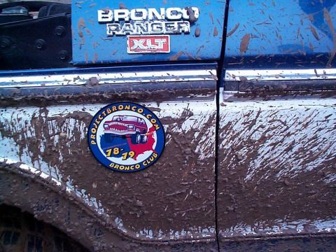 1978 Ford Bronco - Mud-splattered blue 1978 Ford Bronco features a "PROJECTBRONCO.COM 18-19 BRONCO CLUB" sticker on its side.