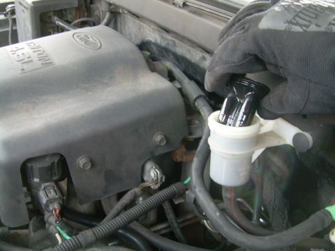 1997 Ford F-150 - A person is adding fluid to the brake fluid reservoir in the engine bay of a vehicle.
