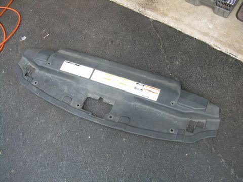 1997 Ford F-150 - A black plastic under-hood shield with warning labels is shown from a top-down perspective.