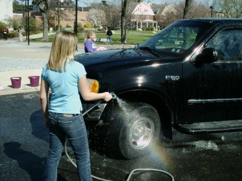 1997 Ford F-150 - A woman washes a black 1997 Ford F-150 truck in a driveway.