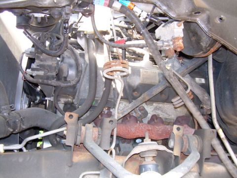 1997 Ford F-150 - Close-up view of engine components, including the exhaust manifold and various hoses and wires.