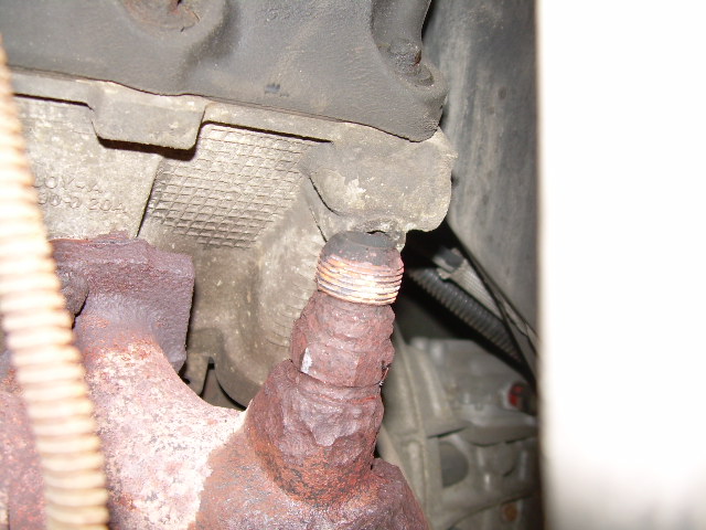 Rusted underbody threaded stud and bracket, close-up from under a vehicle
