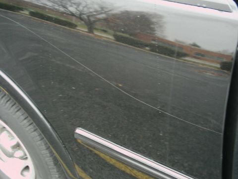 1997 Ford F-150 - Close-up of a black truck's side panel, showing a long scratch and chrome trim detail.
