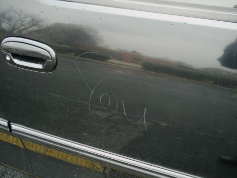 1997 Ford F-150 - The word 'You' is scratched into the side of a dark-colored vehicle.