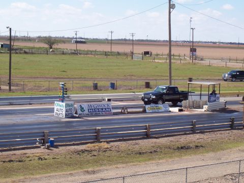 2003 Ford Ranger - A black Ford Ranger pickup truck is positioned at the starting line of a drag strip, with another vehicle visible in the background.
