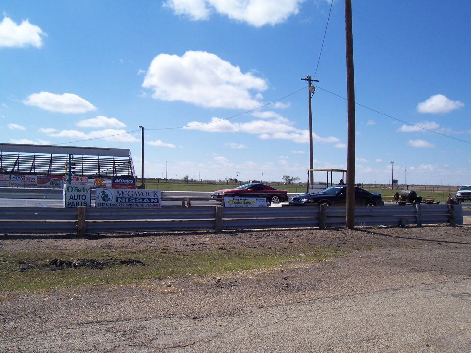 Two cars on drag strip, one red, one black