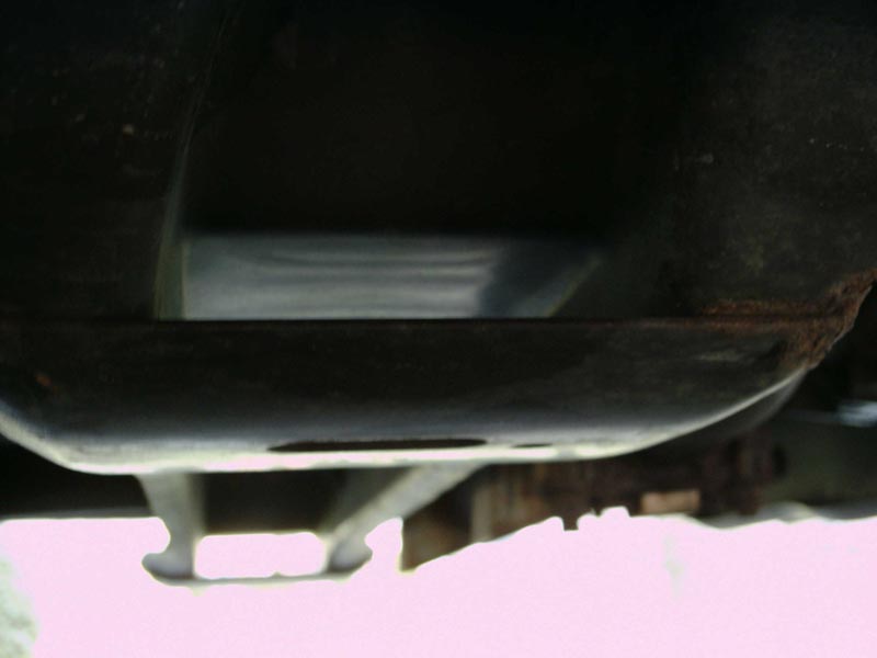 Underside of a vehicle frame with rust on the right side