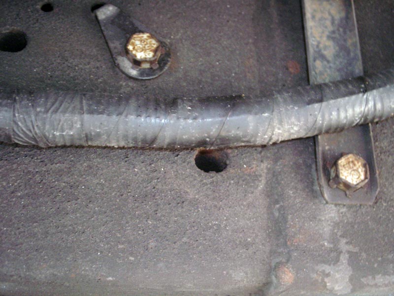 Underside of a vehicle showing a wire loom secured by bolts