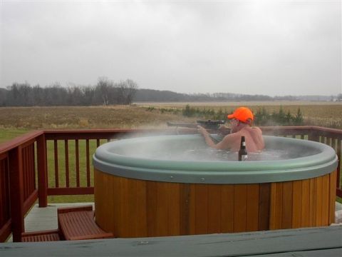 1988 Ford Bronco - A man relaxes in a hot tub while holding a rifle and an orange hat, with a beer bottle nearby.