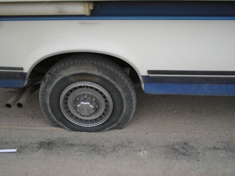 1989 Ford F-250 - Flat tire on the side of a 1989 Ford F-250 truck.
